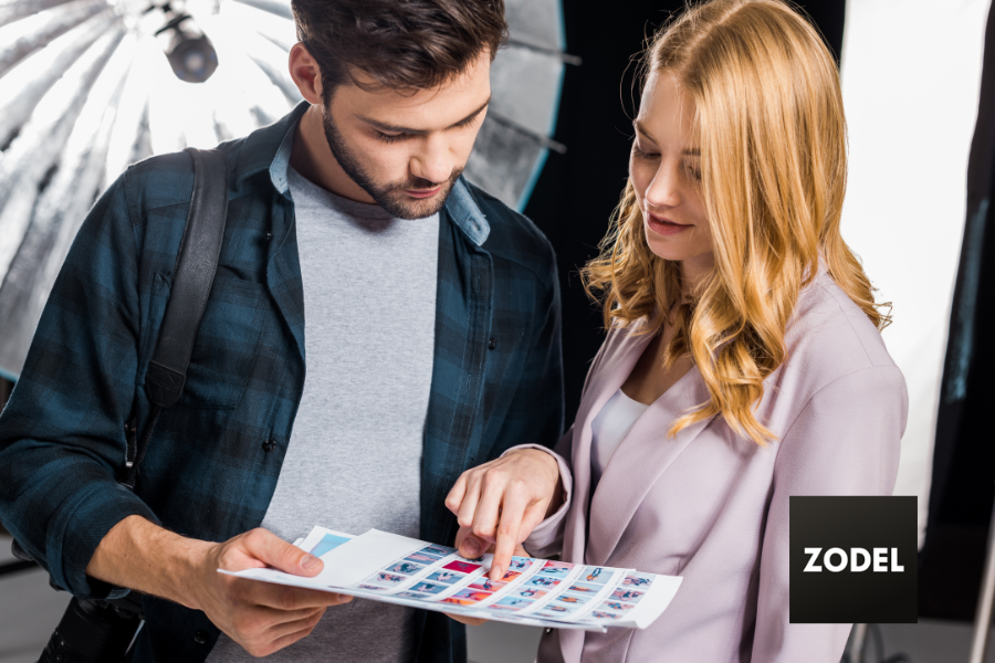 photographer and beautiful young woman looking at pictures in photo studio