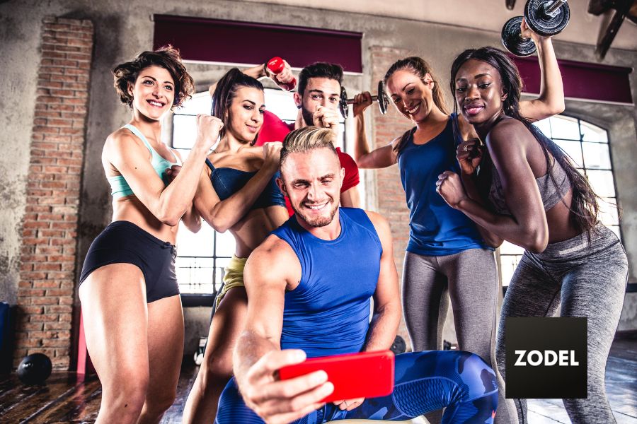 Male fitness model taking a selfie with female fitness models to build personal brand.